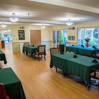 A spacious dining room with neatly arranged tables and chairs, featuring large windows and elegant lighting.