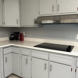 Modern kitchen with a stovetop and white cabinets.