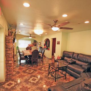 A cozy and spacious living and dining area featuring comfortable seating, a dining table, and ceiling fans.