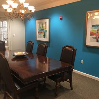 A cozy dining room featuring a wooden table, elegant chairs, and vibrant blue walls adorned with artwork.