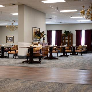 An empty dining area with neatly arranged tables and chairs, decorated with artwork and plants.