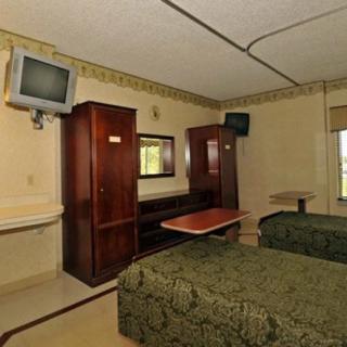 A hotel room with two beds, a wall-mounted TV, wardrobe, and a mirror.