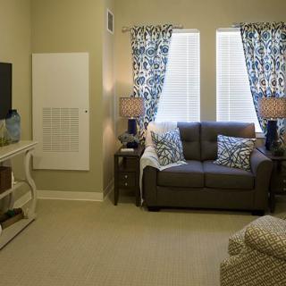 A cozy living room featuring a couch, television, and stylish curtains.