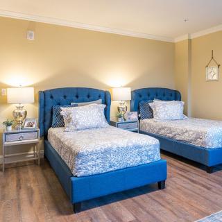 A modern bedroom featuring twin beds with blue headboards and elegant decor.