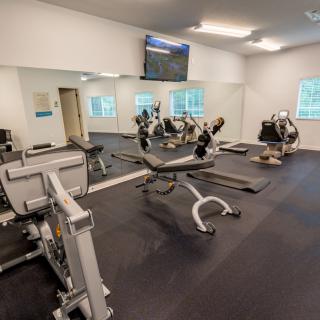 Modern gym with various exercise equipment and mirrors.