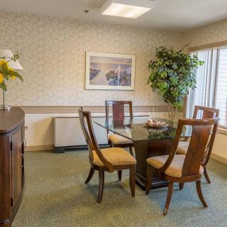 A cozy dining room with a glass table, chairs, and decorative elements like plants and artwork.