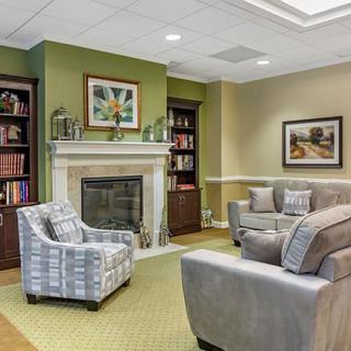 A cozy living room with comfortable seating, a fireplace, and bookshelves adorned with decorative items.