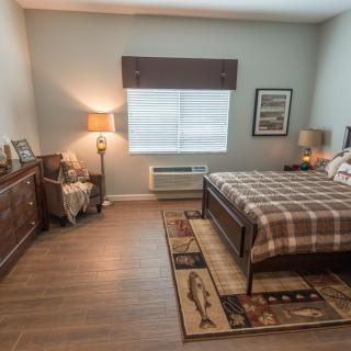 A cozy bedroom with a checkered bedspread, wooden furniture, and warm lighting.