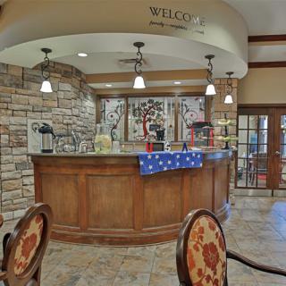 A welcoming reception area with a wooden counter and stone walls, featuring ceiling lights and decorative elements.
