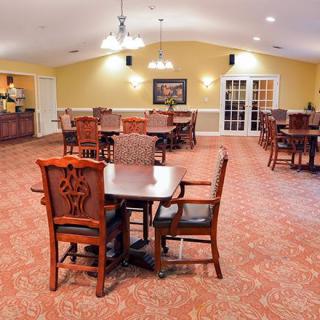 A spacious dining room with tables and chairs arranged neatly on a carpeted floor.