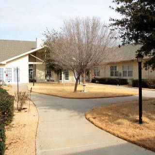 A view of a building with a pathway and trees in the foreground.