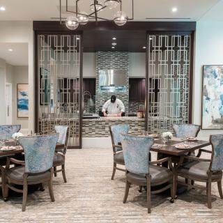 A modern dining room with elegant decor and a chef preparing food.