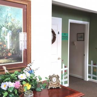 A cozy interior space featuring a painting, floral arrangement, and antique clock.