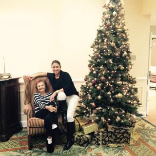 Two people sitting by a decorated Christmas tree in a cozy room.