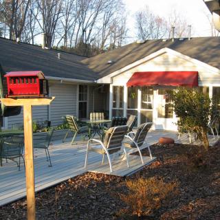 A cozy house with a patio featuring outdoor furniture and a red mailbox.