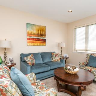 A cozy living room with a blue sofa, patterned armchairs, and a wooden coffee table.