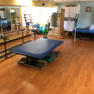A spacious physical therapy room featuring a treatment table and various exercise equipment.
