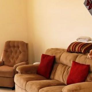A cozy living room with a sofa and armchair featuring red cushions.