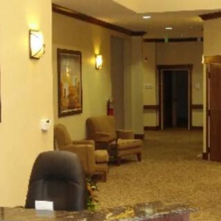 A view of a reception area with chairs placed in a hallway, featuring wall art and ambient lighting.