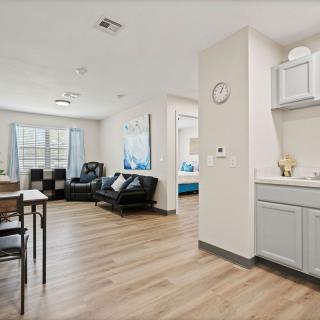 A modern apartment interior featuring a spacious living room, dining area, and a small kitchenette with hardwood flooring.