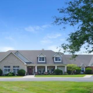 A large suburban house with a well-maintained front yard under a clear blue sky.