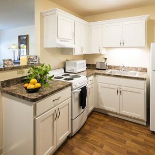 A modern kitchen featuring white cabinetry, granite countertops, and essential appliances.
