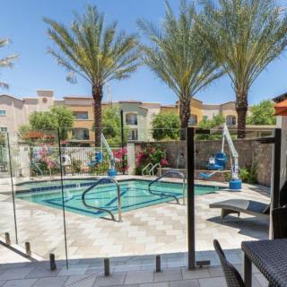 A tranquil outdoor swimming pool surrounded by palm trees in a residential area.