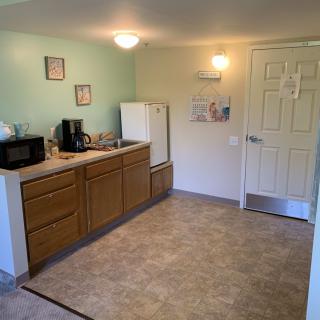 A compact kitchen setup with essential appliances, including a microwave, coffee maker, refrigerator, and sink.