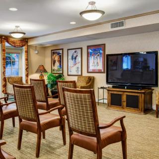 A cozy conference room with arranged chairs facing a television, adorned with framed artwork on the walls.