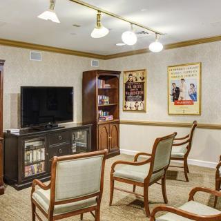 A cozy living room with a TV, wooden chairs, and decorative posters on the wall.