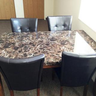 A marble-top dining table with four black chairs.