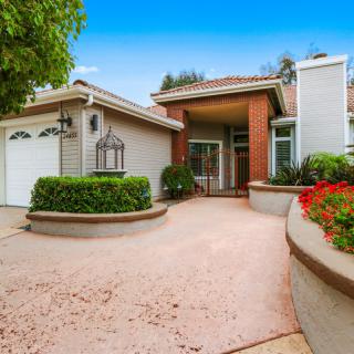 A well-maintained residential house with a spacious driveway and lush garden.