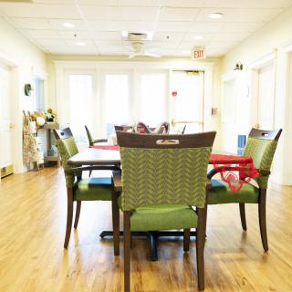 A well-lit dining area with a table and chairs on a wooden floor, creating a welcoming community space.