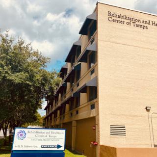 A view of a rehabilitation center with clear signage in front, set against a backdrop of blue skies and greenery.