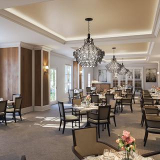 A sophisticated dining room with elegant chandeliers and well-arranged tables and chairs.