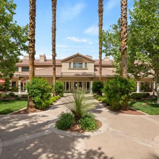 A grand mansion surrounded by palm trees and well-maintained gardens.
