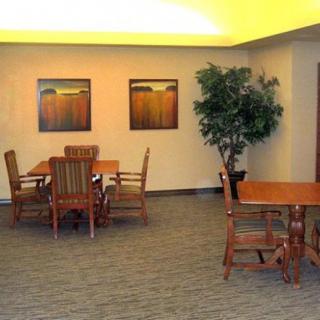 A cozy room with wooden tables and chairs, adorned with artwork on the walls and a potted plant in the corner.
