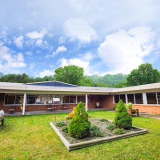 A serene outdoor view of a modern building surrounded by lush greenery and neatly arranged gardens.