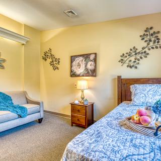 A cozy bedroom with a single bed, decorative wall art, and a small couch.