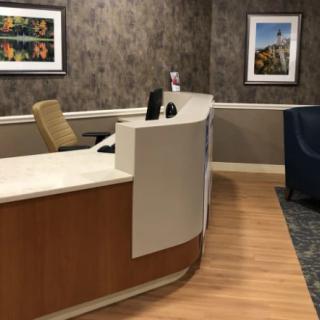 A modern reception desk in an office setting with artwork on the walls.