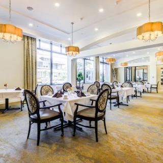 A spacious and elegantly designed restaurant interior, featuring well-set dining tables and stylish lighting.