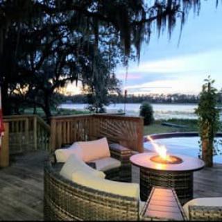 A cozy outdoor patio with a fire pit overlooking a serene lake at sunset.