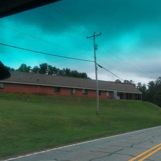 A view of a brick building alongside a road under an overcast sky.