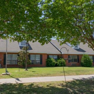 A suburban residential building with a well-maintained lawn and trees in front.