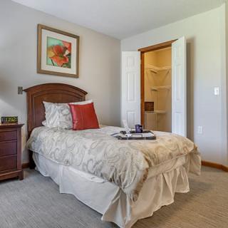 A cozy bedroom with a single bed, decorative pillows, and artwork above the headboard.