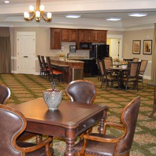 A cozy dining area with a kitchen in the background, featuring wooden tables and chairs.