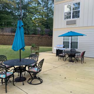A backyard patio with tables, chairs, and umbrellas set up for outdoor seating.