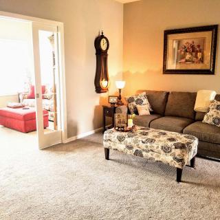 A cozy living room with a grey sofa, patterned ottoman, and soft lighting.