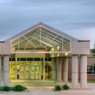 Front entrance of a modern building with glass and columns.