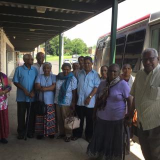 A group of elders gathered near a bus.